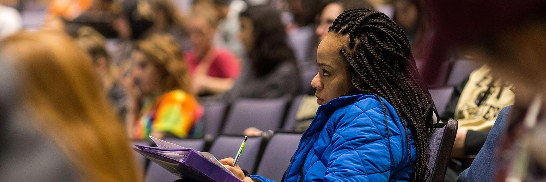 A student takes notes while listening to a lecture.