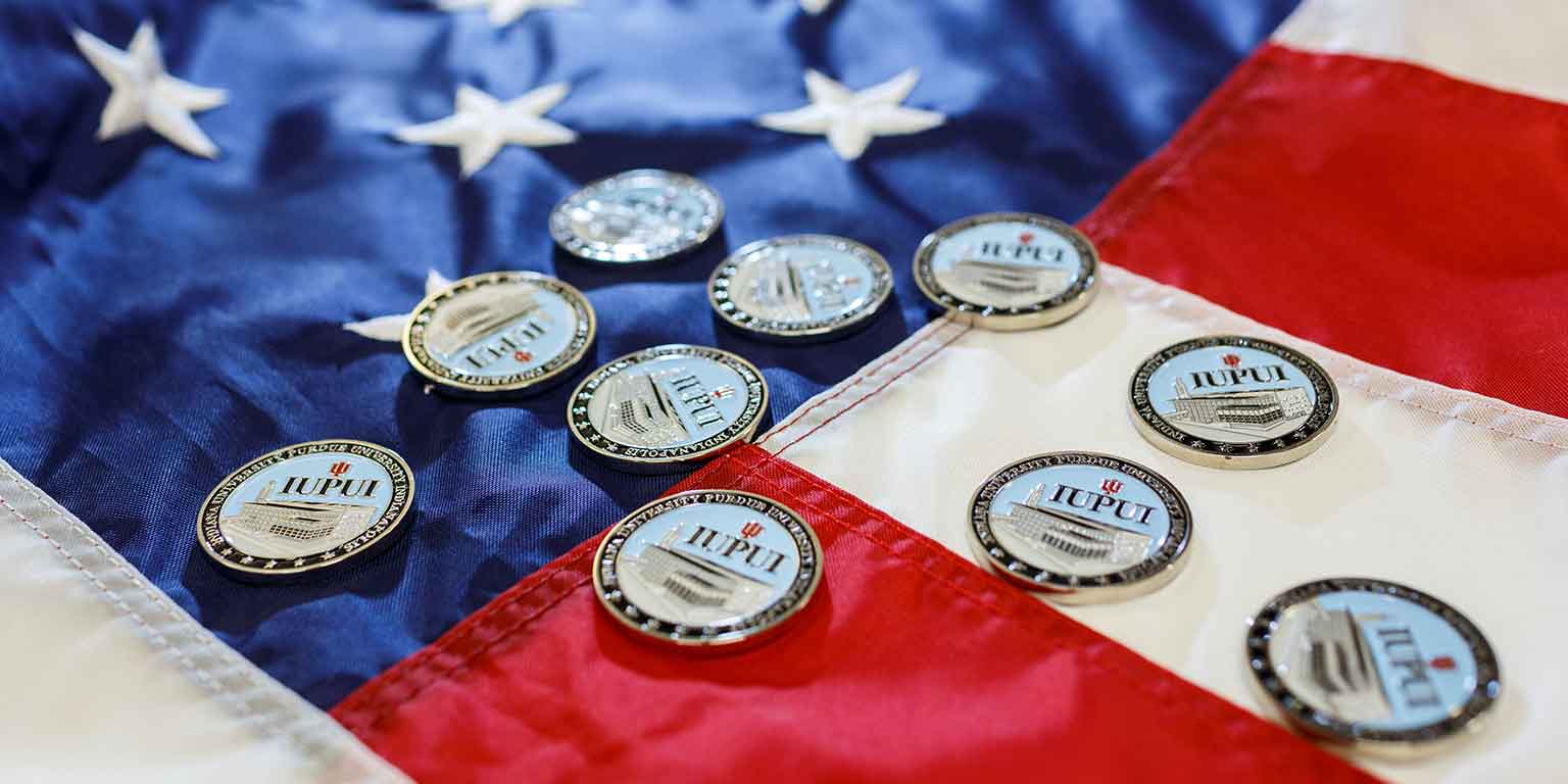 IUPUI medallions lie on an American flag.