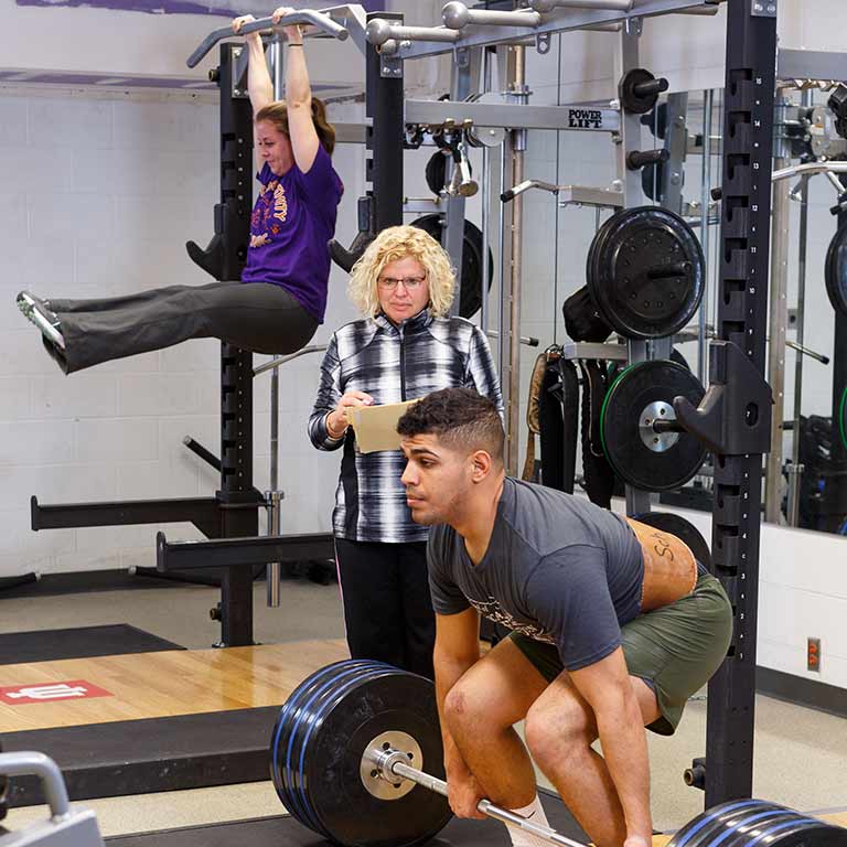 Students work out in a weight room.