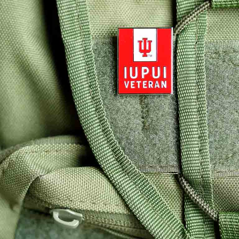 A pin that reads "IUPUI Veteran" pinned to a green backpack